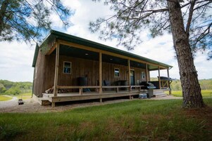 Una cabaña de madera con un porche, mobiliario exterior y vistas del paisaje circundante.