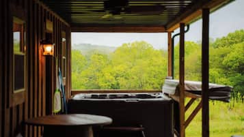 Habitación con vista a un bosque, jacuzzi y una mesa.