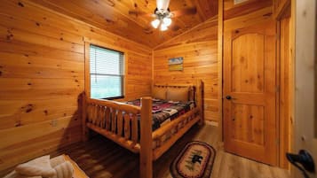 Ein Schlafzimmer einer Holzhütte mit einem Einzelbett, einem Deckenventilator und einer Tür.