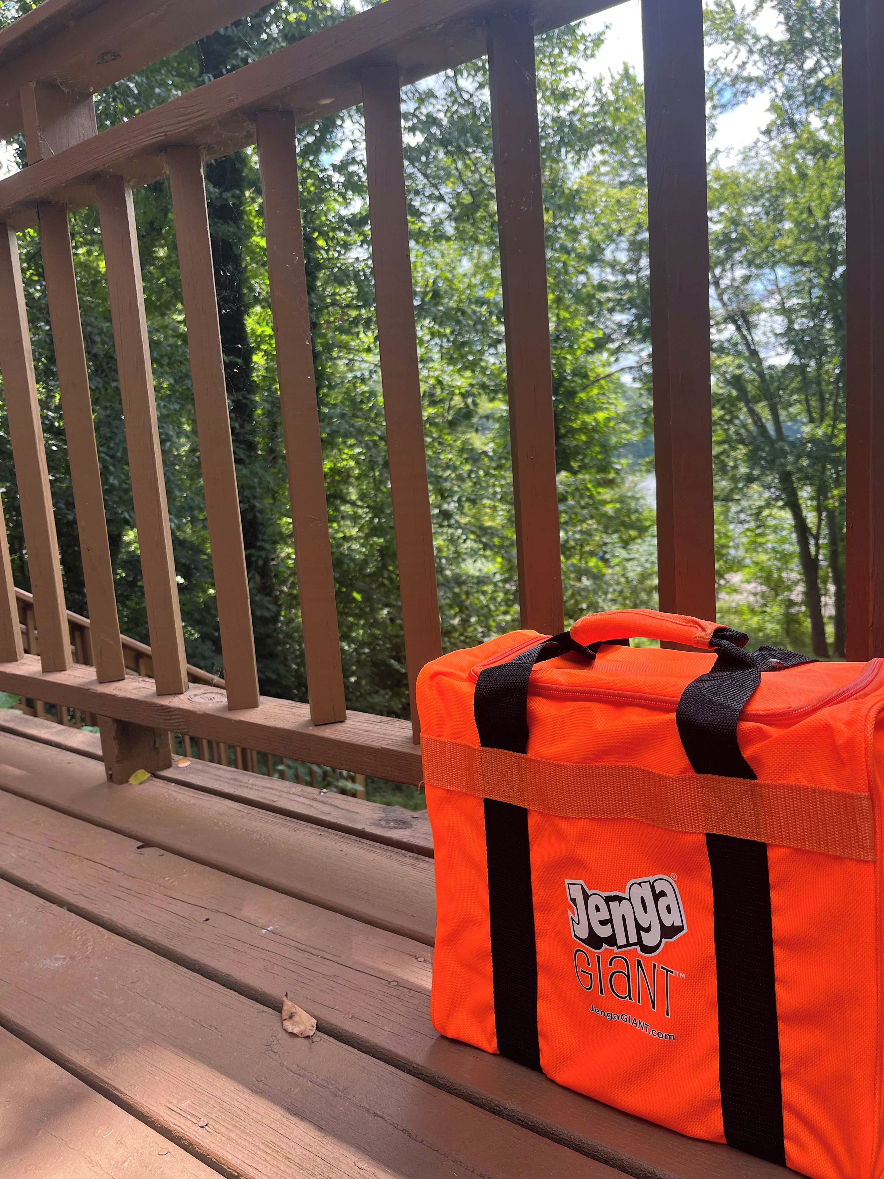 Una terraza de madera con un banco y una bolsa naranja con la marca 'Jenga Giant'.