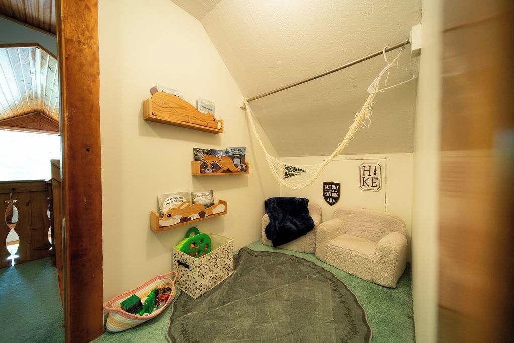 Una habitación acogedora con una hamaca, un pequeño sofá y estanterías con objetos.