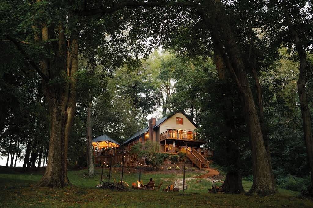 A cabin with a deck and stairs leading to the entrance, surrounded by trees.