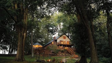 A cabin with a deck and stairs leading to the entrance, surrounded by trees.