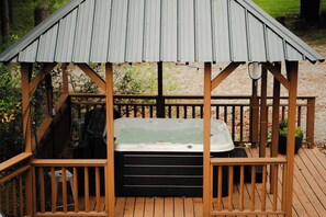 A hot tub under a wooden gazebo with a metal roof, surrounded by a wooden deck. - Waterfront Lake Views Villa With Hot tub in Hocking Hills (Logan)