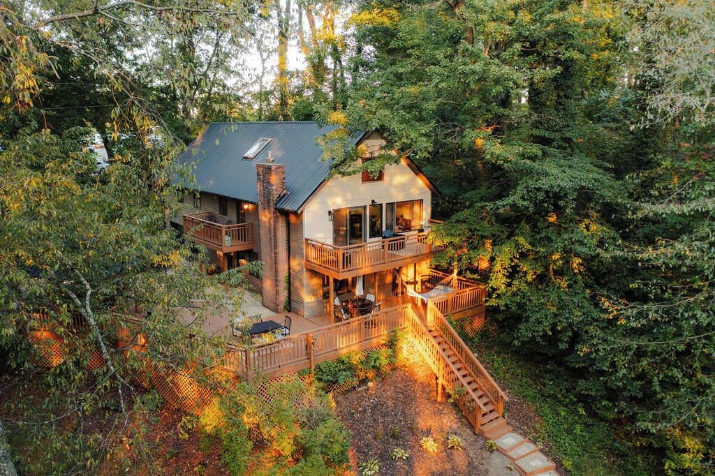 A two-story cabin with a balcony, surrounded by dense forest.