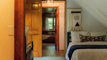 Un dormitorio con una colcha a cuadros, una puerta de madera que da a un pasillo y un tapiz colgado en la pared.