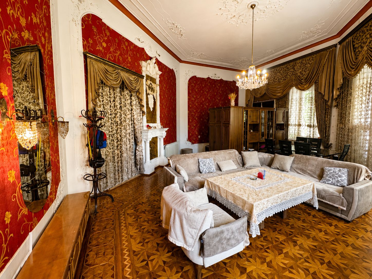 Een ruime woonkamer met een grote hoekbank, een open haard en een kroonluchter.