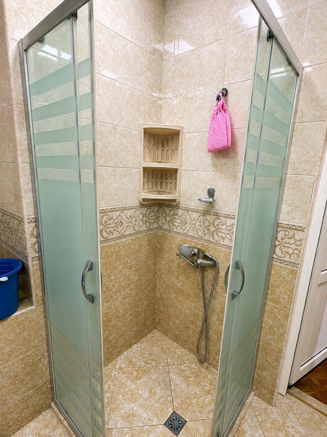 A glass-enclosed shower stall with a showerhead and a handheld shower attachment.