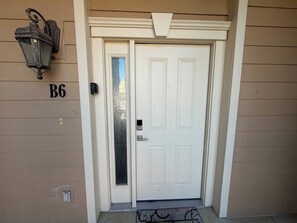 A white door with a frosted glass panel, a black doorbell, and a number 'B6' on the wall.