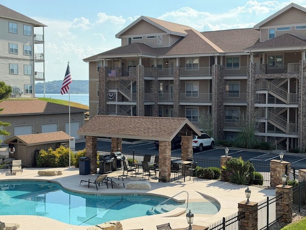 A multi-story hotel with a pool area, outdoor seating, and a view of the surrounding landscape.