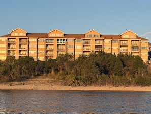 A multi-story hotel with balconies, situated by a body of water. - Escape to Sunset Shores! Come for the lake, golf or Branson-Stay for the suns... (Hollister)