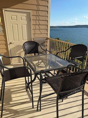 A balcony with a glass table and four wicker chairs, overlooking a body of water. - Escape to Sunset Shores! Come for the lake, golf or Branson-Stay for the suns... (Hollister)