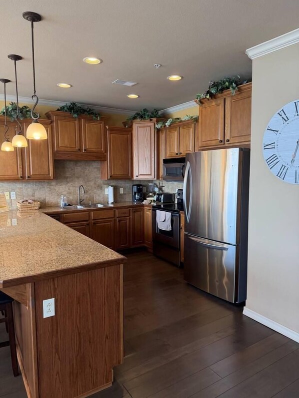 A kitchen with wooden cabinets, stainless steel appliances, and a clock on the wall.
