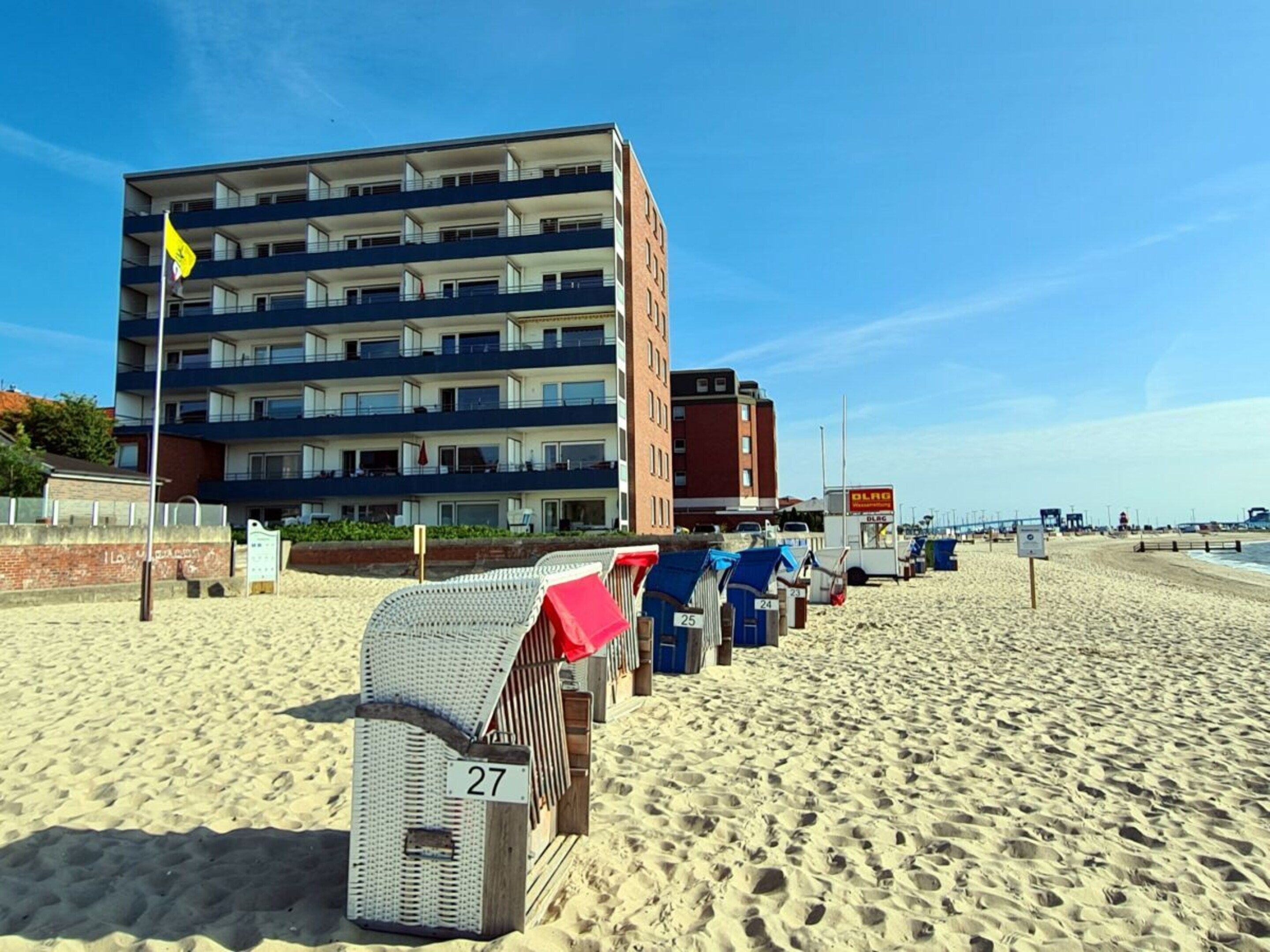 Um hotel à beira-mar com vários andares, área externa para sentar e céu claro.