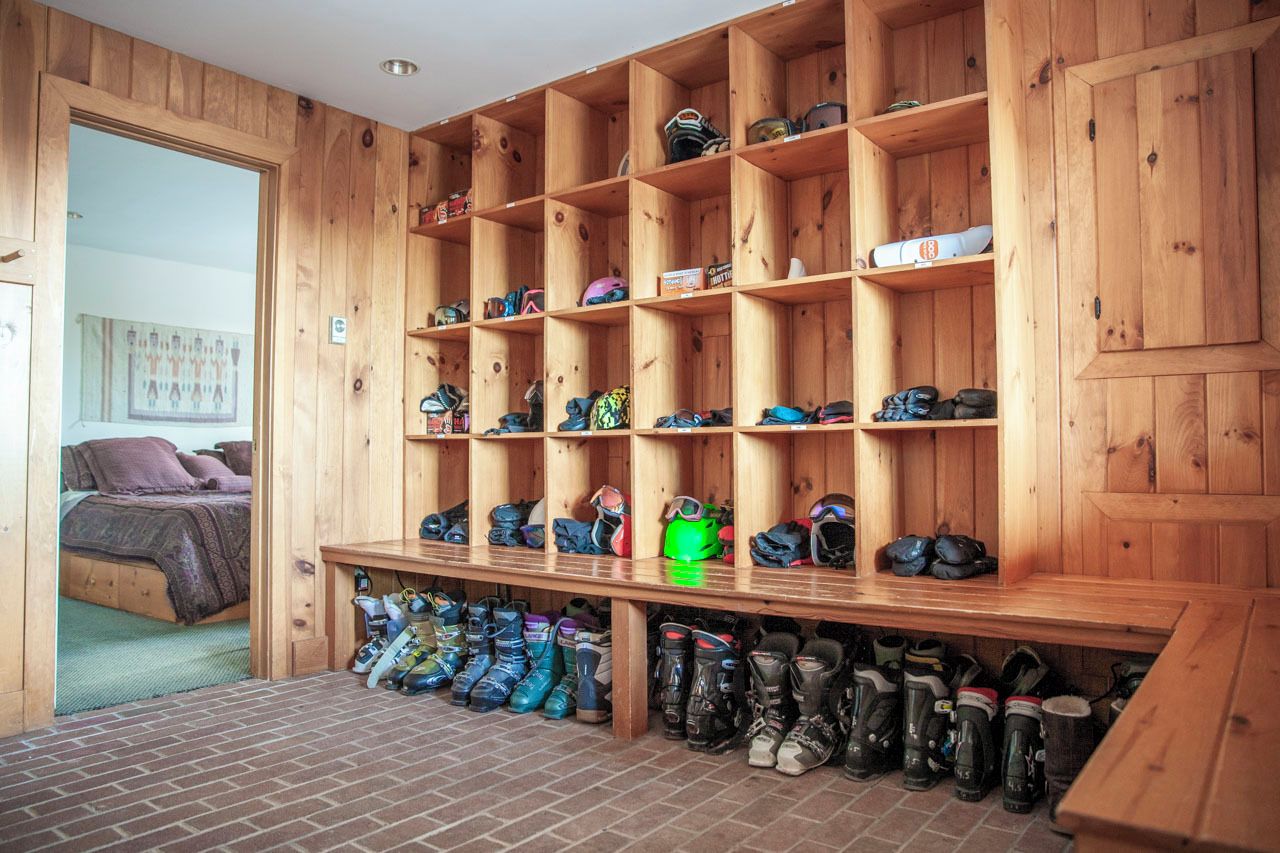 Een kamer met een schoenenrek van hout en een bed.