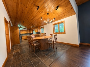 A spacious kitchen with wooden cabinets, a central island, and a dining area with chairs.
