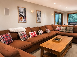 A cozy living room with a brown sectional sofa, plaid pillows, and a wooden coffee table.