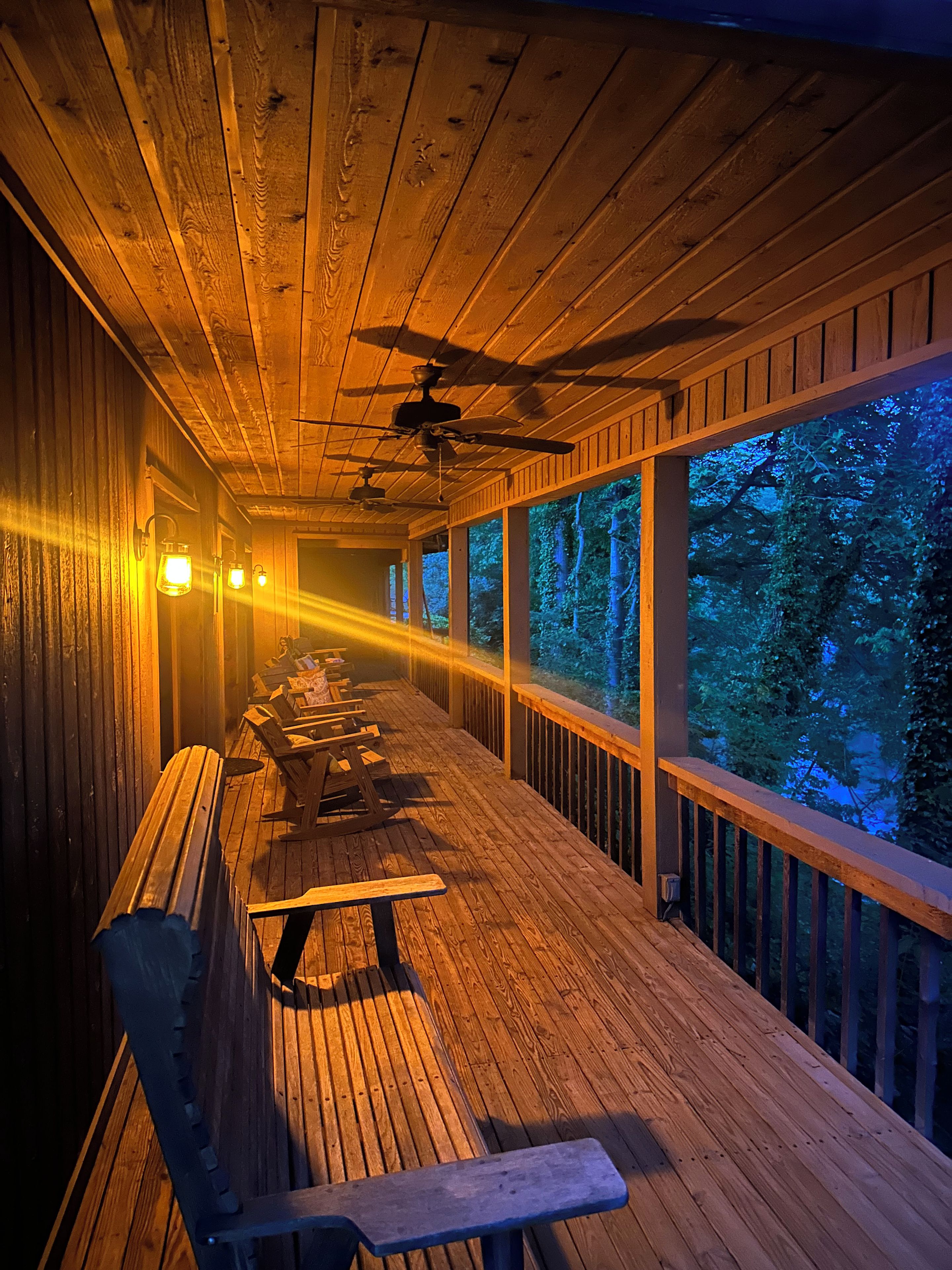 A covered outdoor deck with wooden benches and a ceiling fan.