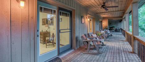 A covered porch with wooden flooring, a ceiling fan, and outdoor seating.