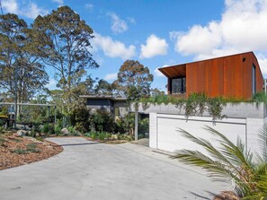 A modern house with a concrete driveway, surrounded by trees and shrubs. - Rosedale House Beachside Luxury Coastal Retreat (Rosedale)