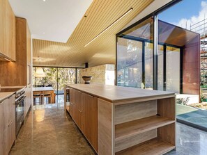 A modern kitchen with wooden cabinetry, a central island, and large windows.