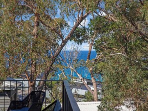 A balcony with a view of the ocean, surrounded by trees.