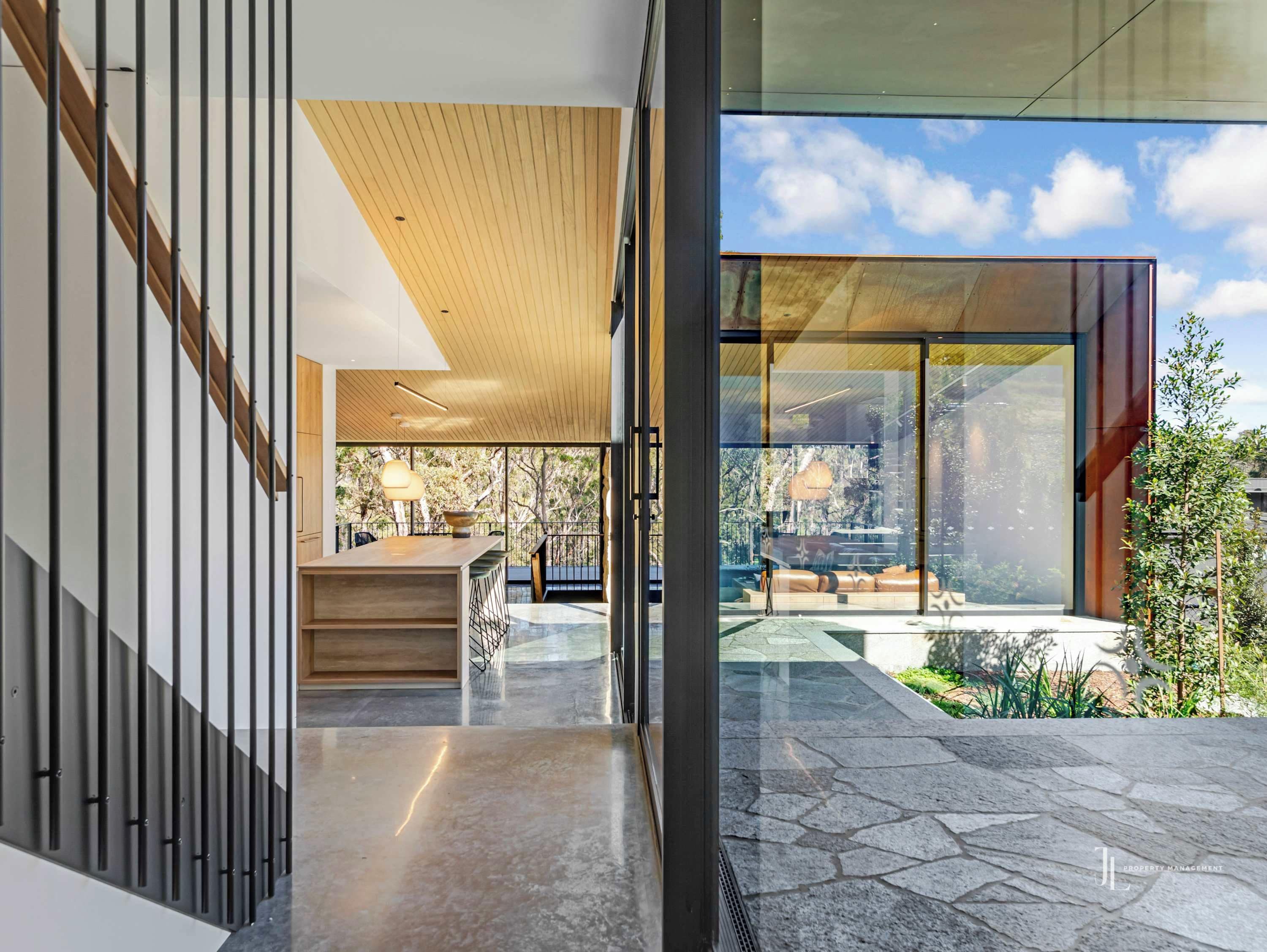 Un interior moderno con una escalera, un área de comedor y vistas al exterior.