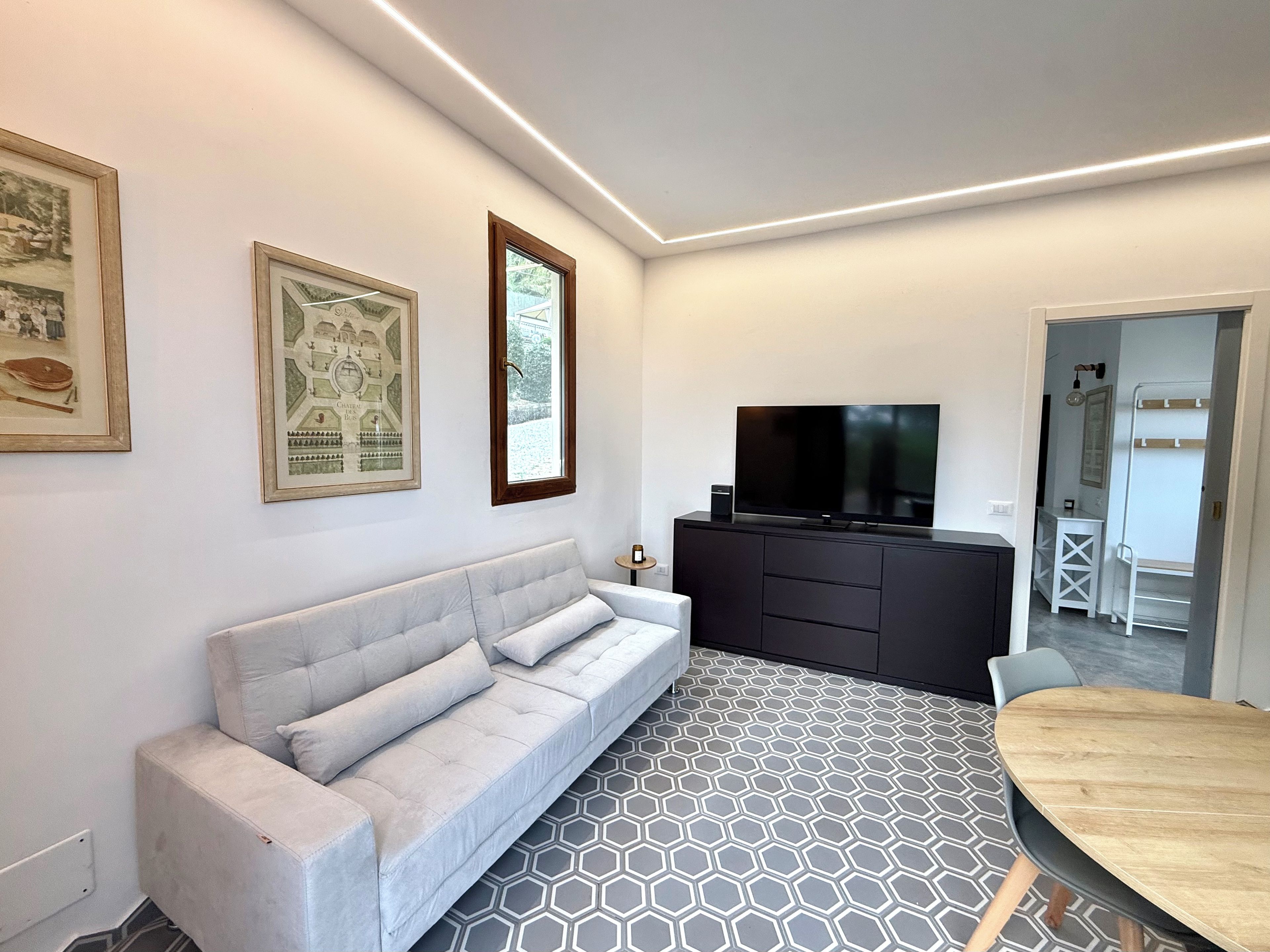 Un salon moderne avec un canapé, un téléviseur et un sol à motifs.