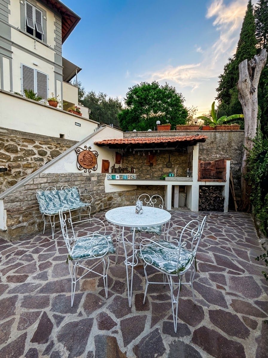 An outdoor patio with stone flooring, a round table, and metal chairs.