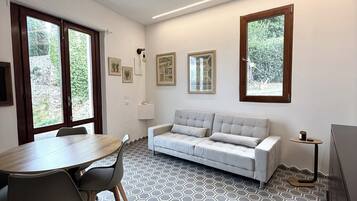 Ein modernes Wohnzimmer mit einer Couch, einem Esstisch mit Stühlen und einem Fernseher.
