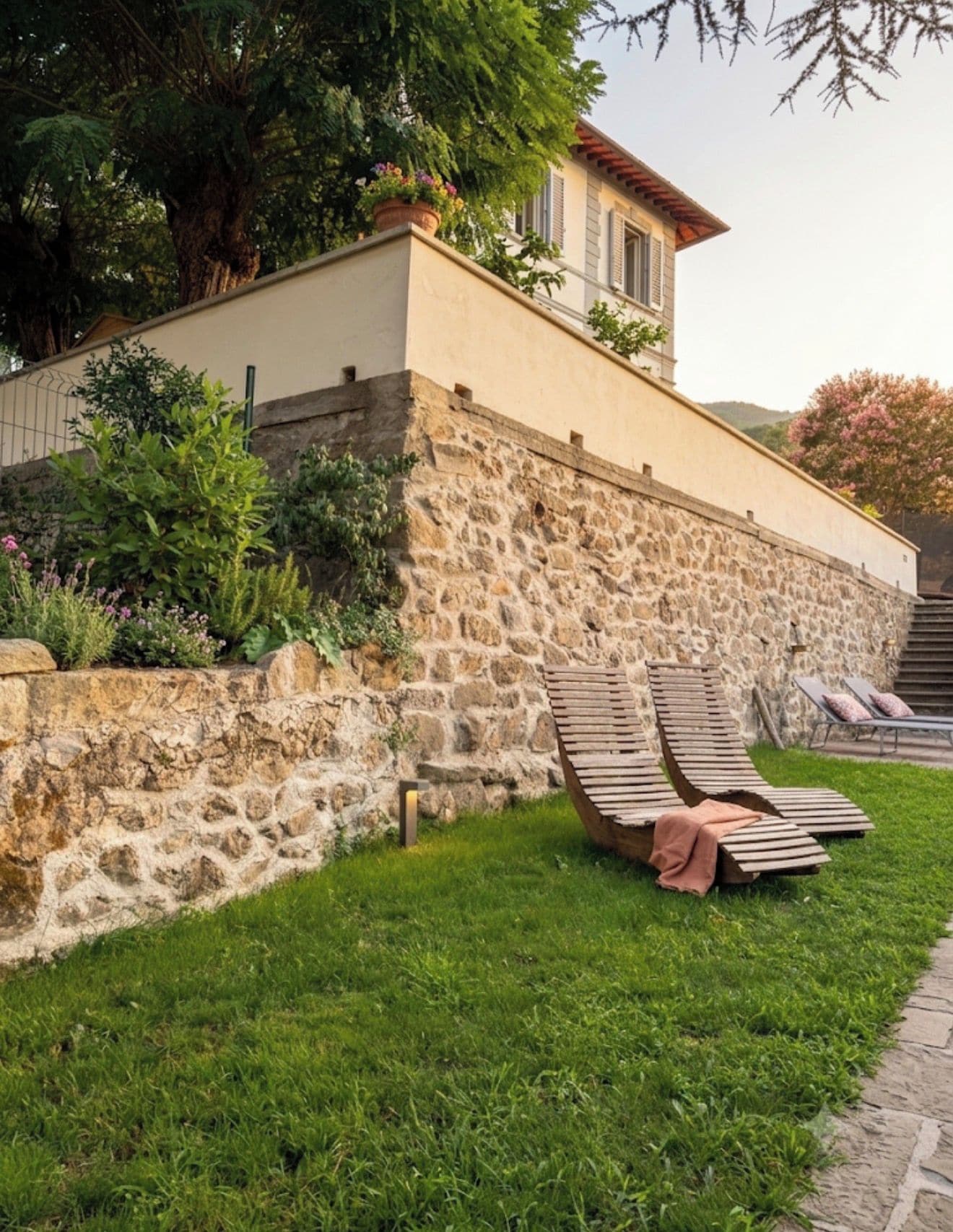 A stone wall with a grassy area and a wooden bench.