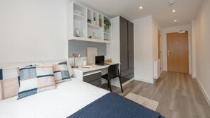 Ein modernes Schlafzimmer mit Bett, Schreibtisch und Kleiderschrank.