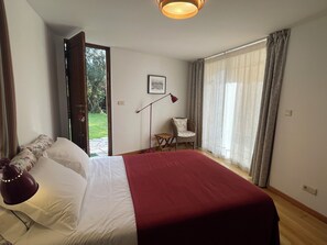 A bedroom with a bed, a chair, a desk, and a window with curtains. - Countryside Sanctuary | Casa de Santiago Ponte de Lima (Facha)