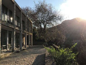 A building with a covered outdoor seating area and a large tree in the background. - Countryside Sanctuary | Casa de Santiago Ponte de Lima (Facha)
