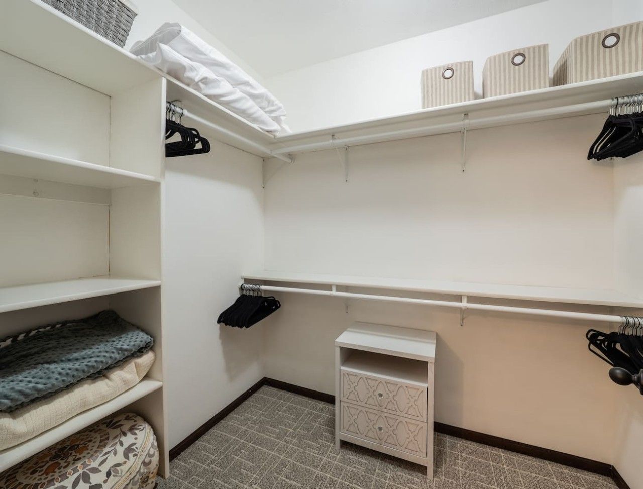Un armario amplio con estantes abiertos, un mueble pequeño y espacio para colgar.