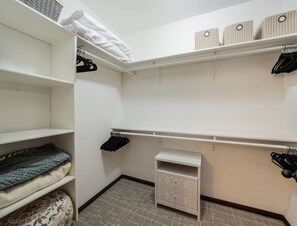 A walk-in closet with open shelves, a small cabinet, and hanging storage.