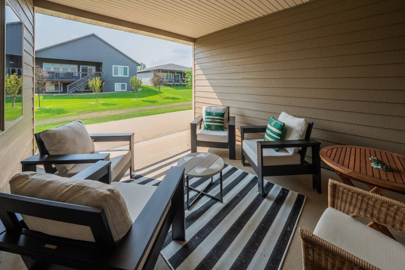 A covered outdoor seating area with a view of a residential building.