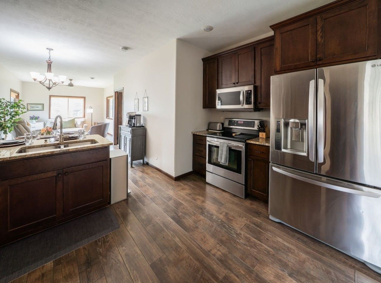 A modern kitchen with dark wood cabinets, stainless steel appliances, and a central island with a sink.