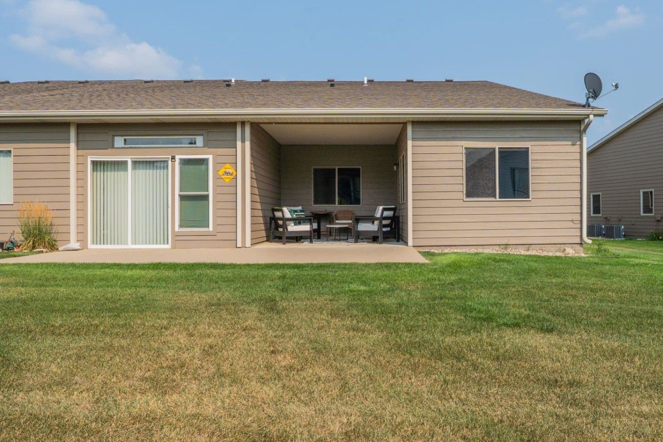 A single-story house with a covered patio area, a sliding glass door, and a satellite dish.
