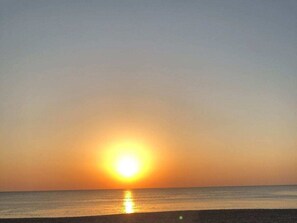 Un coucher de soleil sur une mer calme, avec un horizon dégagé.