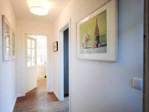 A hallway with a door leading to a room, a framed picture on the wall, and a light fixture on the ceiling. - Holiday Home With 2 Bedrooms (Sylt)