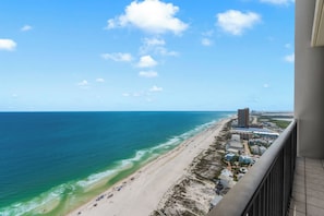 Blick aufs Meer vom Balkon mit Strand und blauem Himmel.