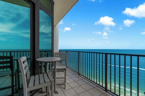 Ein Balkon mit Tisch und Stühlen mit Blick auf das klare, blaue Meer.