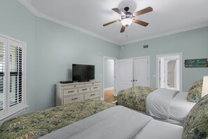 Ein Schlafzimmer mit zwei Betten, einem Deckenventilator, einem Fernseher auf einer Kommode und einem Schild an der Wand.