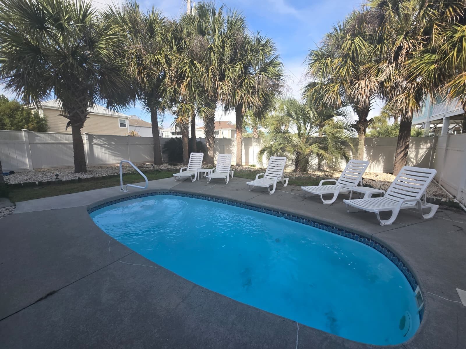 A swimming pool with white lounge chairs and palm trees.