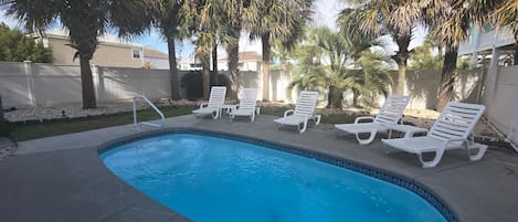 A swimming pool with white lounge chairs and palm trees.