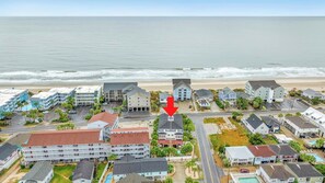 Un hotel frente al mar con varias construcciones, un estacionamiento y vistas al océano.