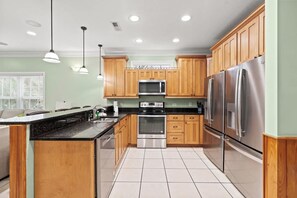 A modern kitchen with wooden cabinets, stainless steel appliances, and pendant lighting. - 5BR | Sleeps 14 | Pool | Steps To Beach | 601A (Murrells Inlet)