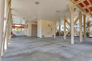 An indoor covered area with a concrete floor, structural beams, and a red roof. - 5BR | Sleeps 14 | Pool | Steps To Beach | 601A (Murrells Inlet)