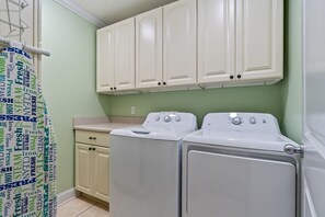A laundry room with two stacked washers and dryers, a countertop, and cabinets above. - 10 BR | Sleeps 28 | Pool | Steps To Beach | 601AB (Murrells Inlet)